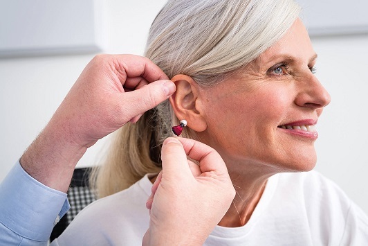 Ältere Frau bekommt ein Hörgerät vom Hörakustiker für besseres Hören angepasst.